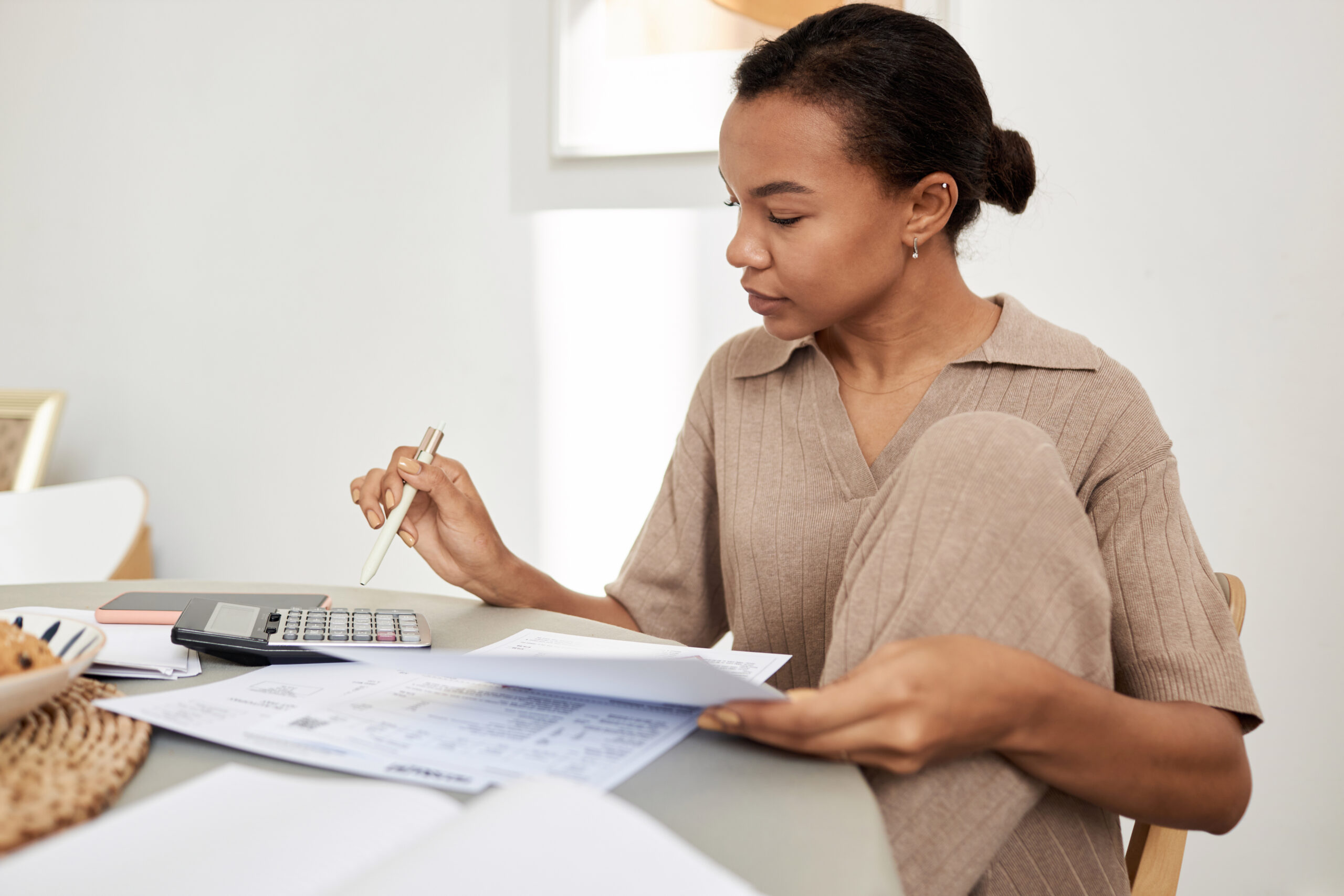 Young Black woman doing taxes at home and using calculator Young woman doing taxes at home and using calculator